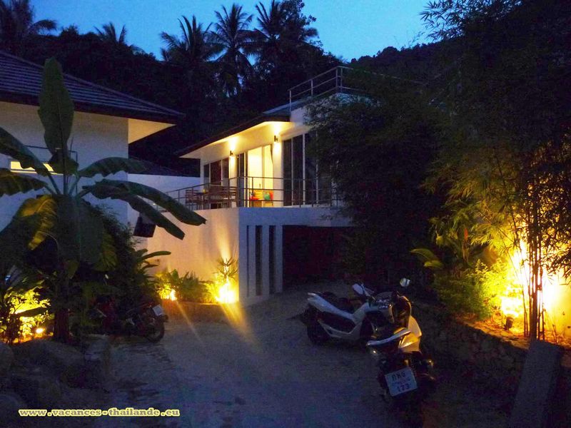 villa with swimming pool terrace greenery and exposed stone wall lit up at night in the resort of Chaweng koh Samui